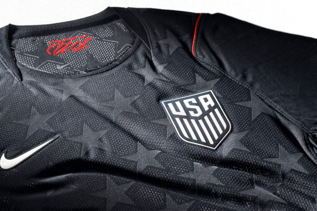 Das USA Away Kit 2026 setzt auf ein dunkles Dark-Obsidian-Design mit subtil eingewebtem Sternmuster und steht für einen minimalistischen, zeitlosen Look auf und neben dem Platz. Quelle: <a href="https://about.nike.com/en/newsroom/collections/nike-football-unveils-2026-federation-kits-featuring-aero-fit-performance-cooling-technology/USA-Away-Kit-5" target="_blank" rel="noopener">Nike</a>.